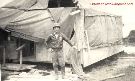 Photo of Vicent Dauro standing by a tent after a Hurricane hit the Camp.