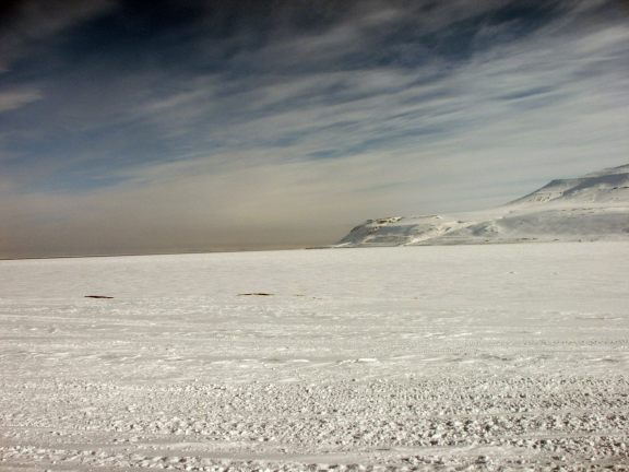 An ocean picture of the arctic ocean and the remaining winter snow on the mountain outside of Barentsburg.