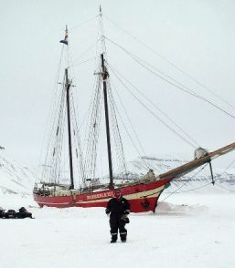 A ship frozen in the ice at the edge of a glacier.