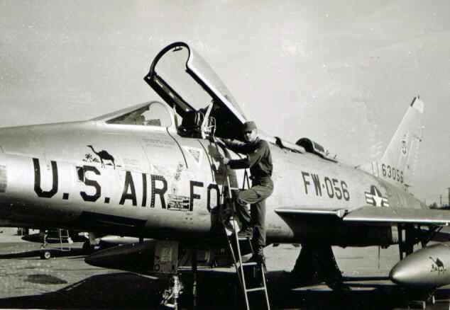 Pete Byam standing on a F-100 SuperSabre Jet Fighter in Saudi Arabia